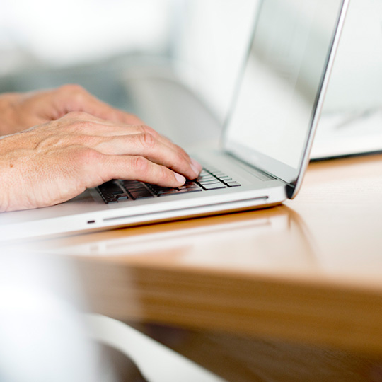 close up of hands typing on a laptop